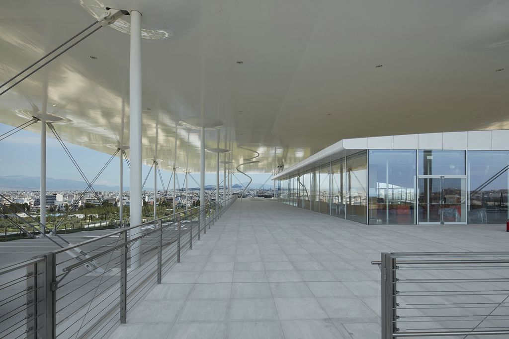 a walkway with white pillars and windows